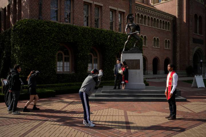 Graduating seniors take photos around the Tommy Trojan statue on the University of Southern Cal ...