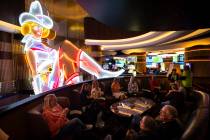People relax by the historic Vegas Vickie neon sign at Circa during a tour of Fremont Street as ...