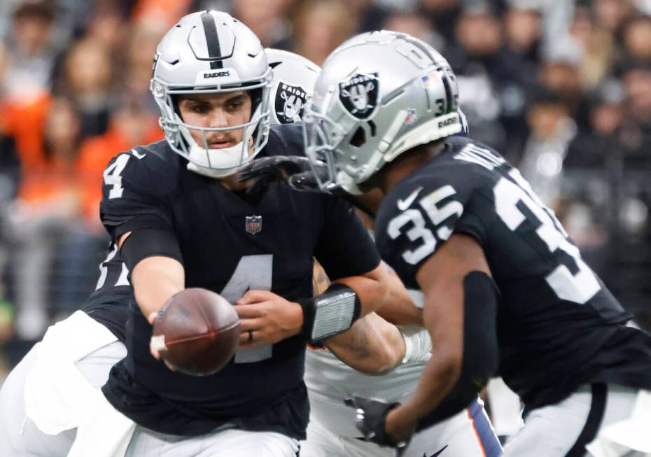 Raiders quarterback Aidan O'Connell (4) hands off to Raiders running back Zamir White (35) duri ...