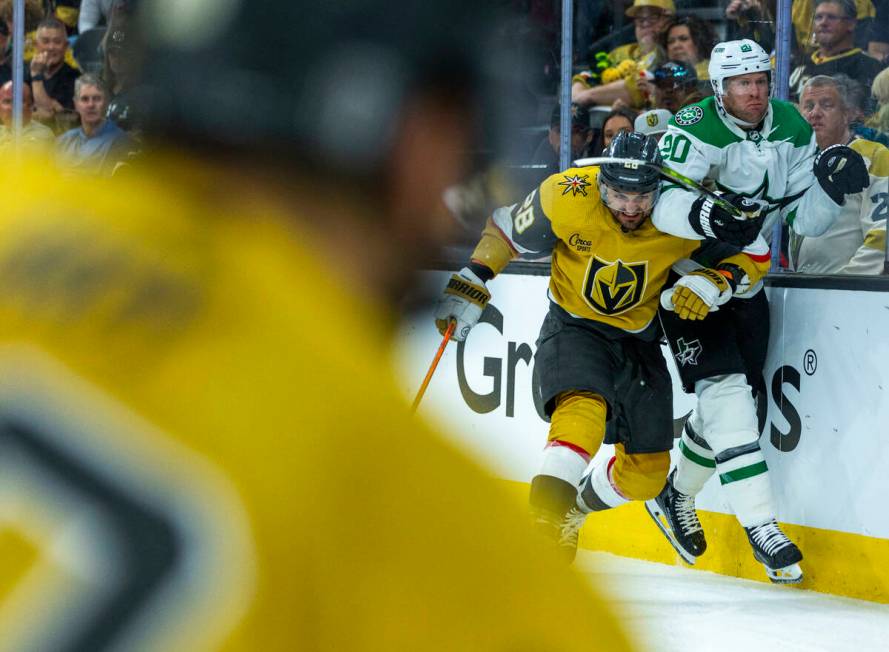 Golden Knights left wing William Carrier (28) drives Dallas Stars defenseman Ryan Suter (20) in ...