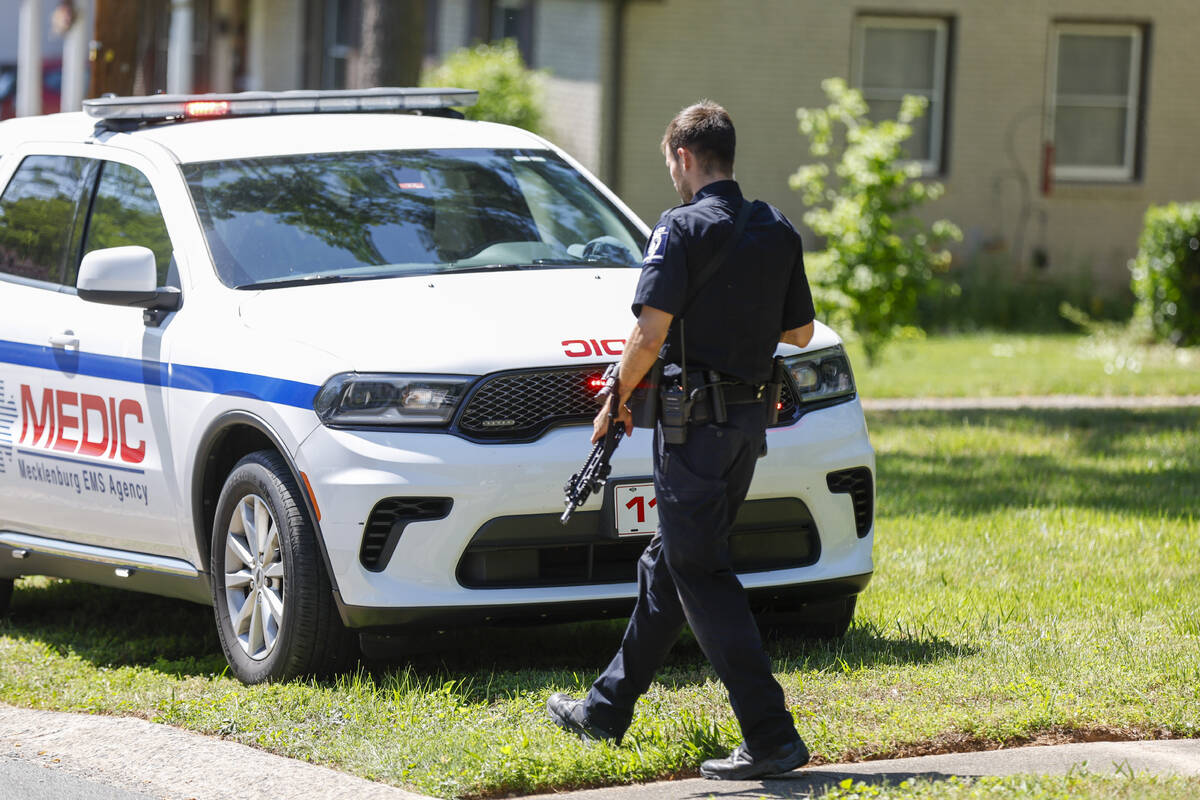 A Charlotte-Mecklenburg Police Department officer walks carrying a gun in the neighborhood wher ...