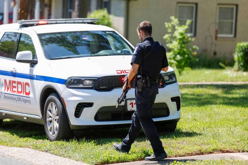 A Charlotte-Mecklenburg Police Department officer walks carrying a gun in the neighborhood wher ...