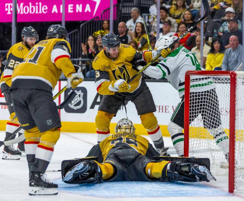 Golden Knights goaltender Logan Thompson (36) smothers a puck as teammate defenseman Brayden Mc ...