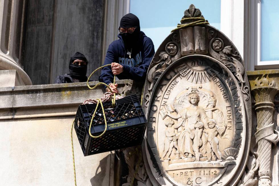 Pro-Palestinian protestors who are occupying Hamilton Hall lift a milk crate with supplies at C ...