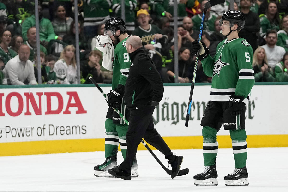 Dallas Stars' Tyler Seguin, left, is escorted off the ice by a staff member and Nils Lundkvist, ...