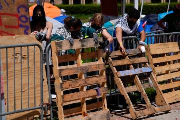 Demonstrators restore a protective barrier at an encampment on the UCLA campus, the morning aft ...