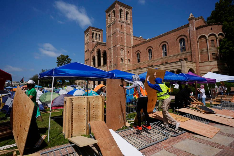 Demonstrators restore a protective barrier at an encampment on the UCLA campus, the morning aft ...