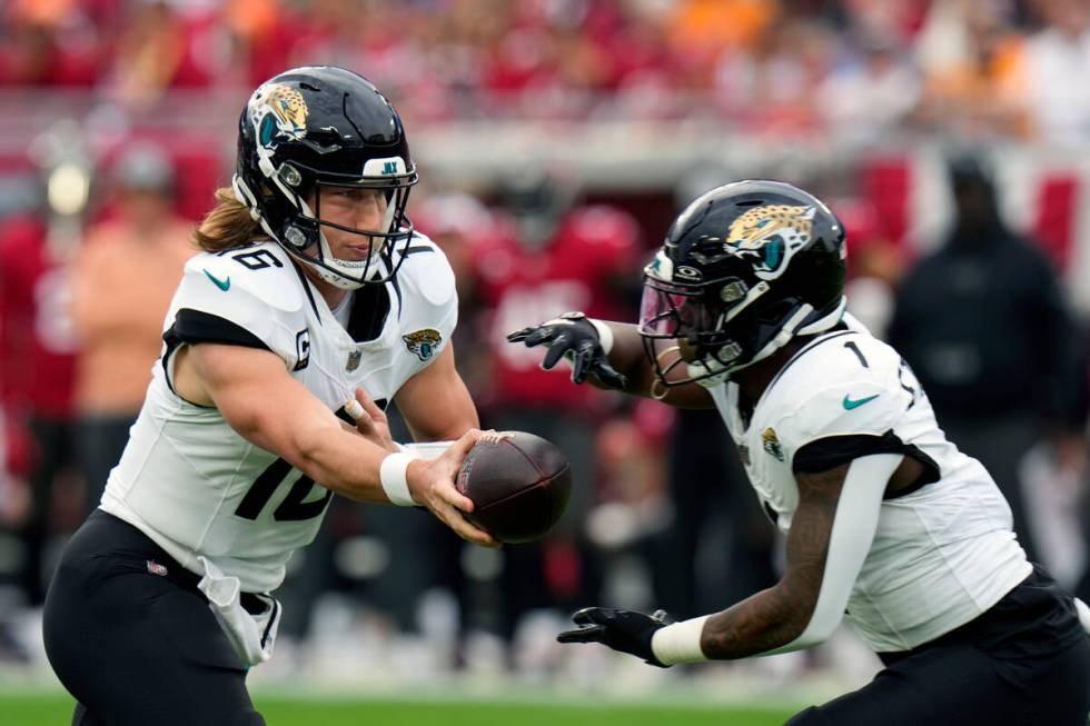 Jacksonville Jaguars quarterback Trevor Lawrence (16) hands off the ball to running back Travis ...