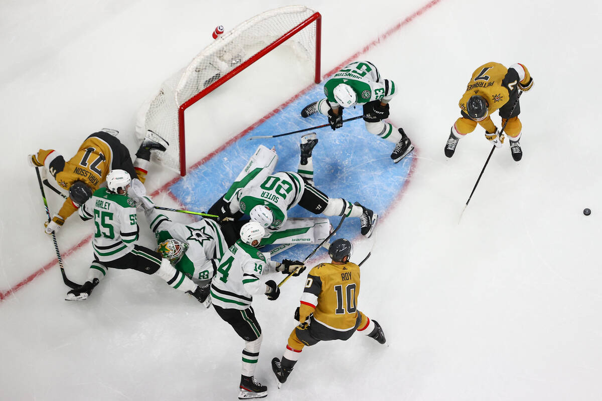 Stars goaltender Jake Oettinger (29) falls to the ice while saving the puck as a sea of players ...