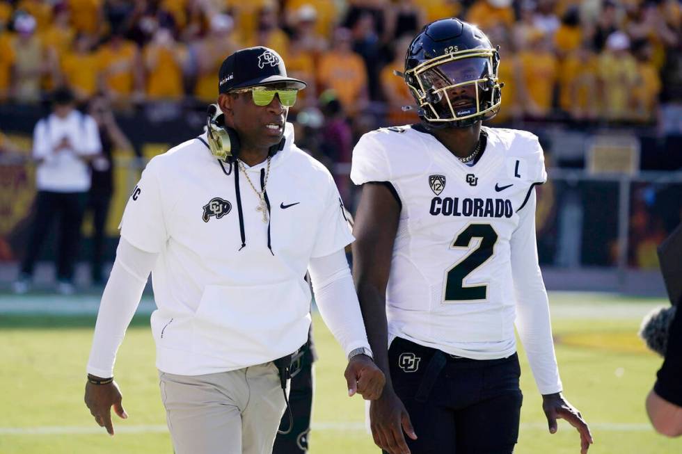 Colorado head coach Deion Sanders, left, talks with his son and starting quarterback Shedeur Sa ...