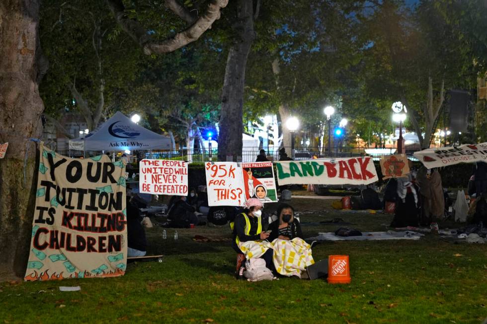 People stand guard outside an encampment set up by pro-Palestinian demonstrators on the campus ...