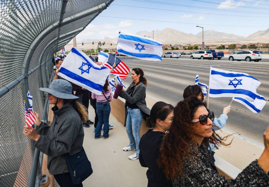 Participants wave flags and signs at passing cars on the Charleston bridge overpass on the 215 ...