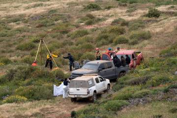 Rescue workers, forensics and prosecutors work in a waterhole where human remains were found ne ...