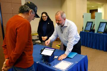 Dan Kulin, right, manager Election Administration, demonstrates how to register at a pooling st ...