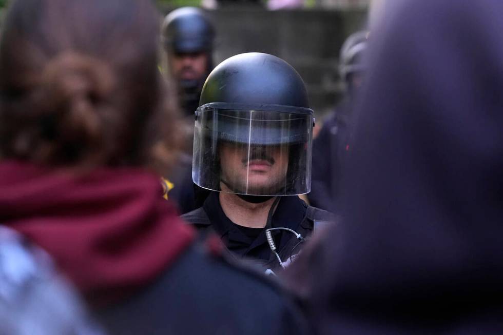 A police officer stands guard blocking pro-Palestinian protesters from returning to their encam ...