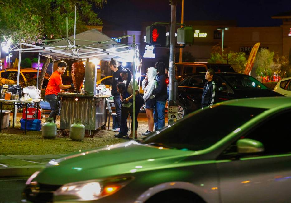 Jaime Melendez, left, prepares tacos al pastor at his taco stand at the corner of Durango Drive ...