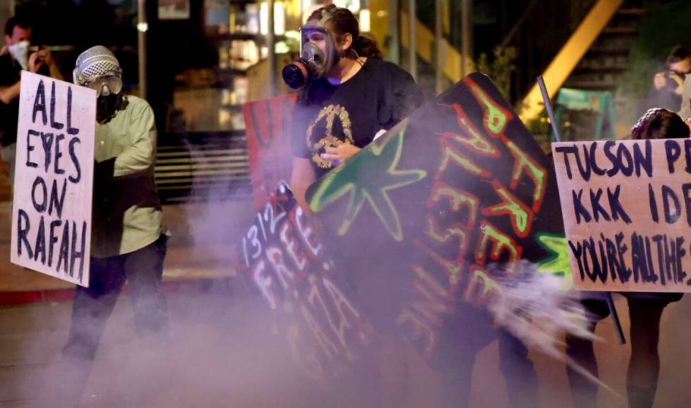 Demonstrators retreat along University Boulevard in a cloud of teargas as law enforcement offic ...