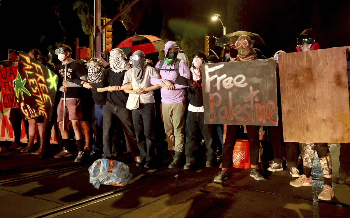 Demonstrators lock arms near the intersection of Park Avenue and University Boulevard as they c ...