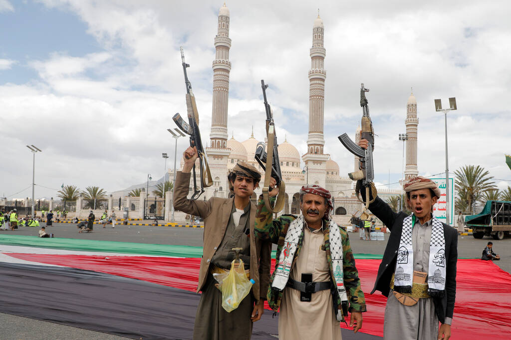 Houthi supporters raise their machine guns during a rally against the U.S.-led strikes against ...