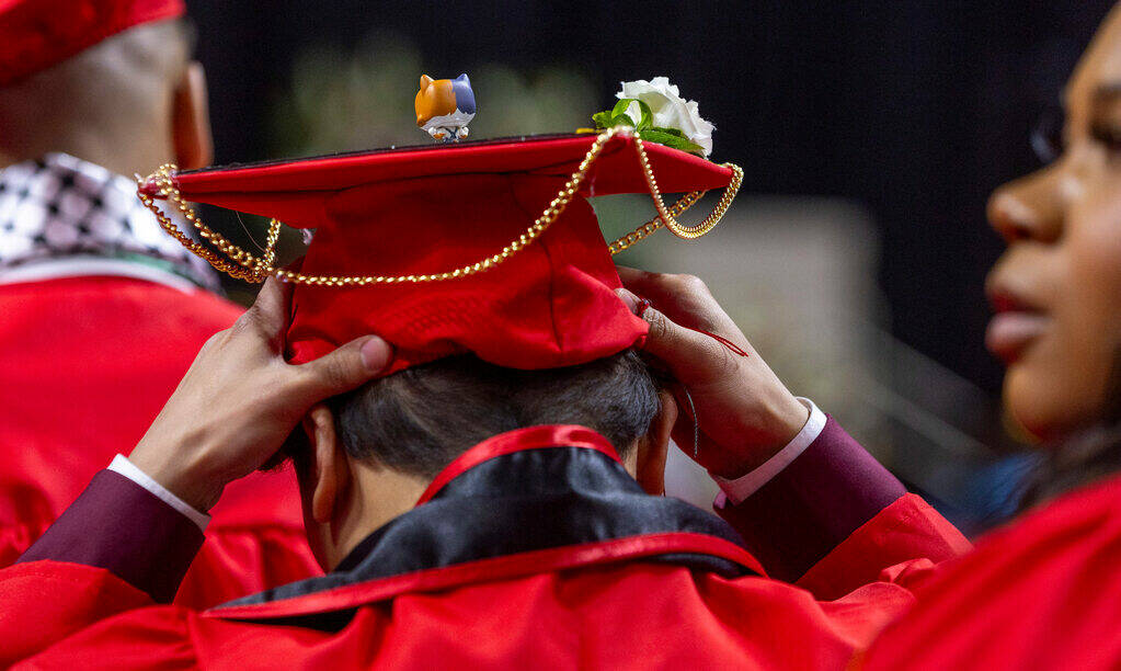 A graduate adjusts a custom mortar board during UNLV spring graduation commencement exercises a ...