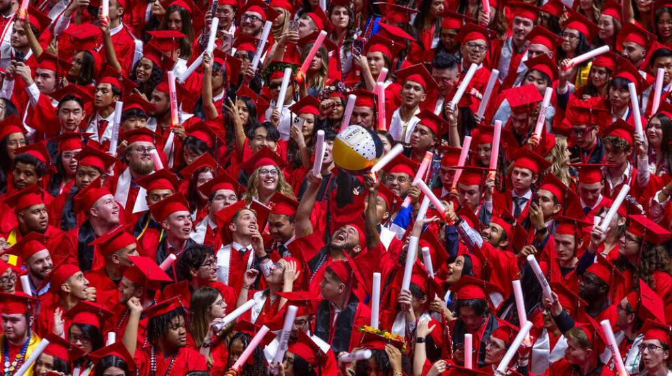 A beach ball is swatted about the group as graduates cheer and applaud by waving light sticks a ...