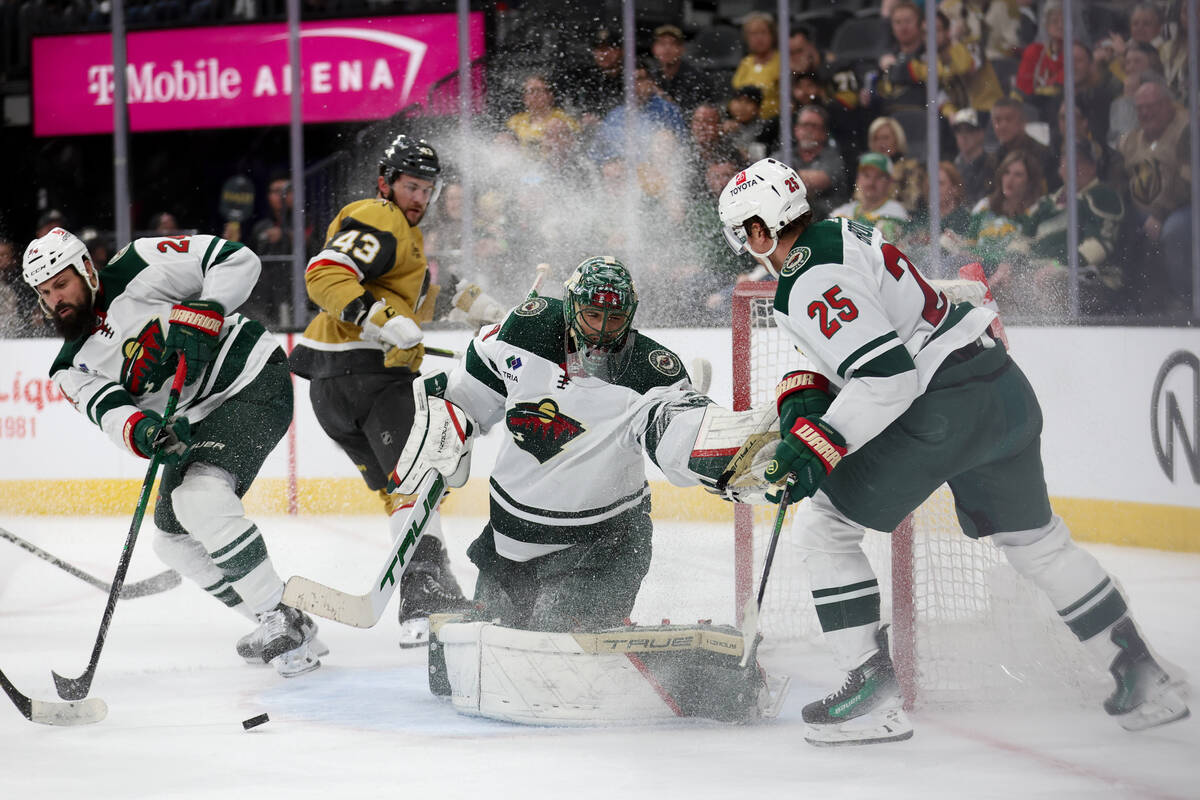 Golden Knights center Paul Cotter (43) watches his shot as Wild defenseman Zach Bogosian (24), ...