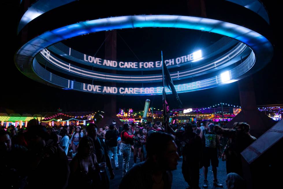 Attendees dance below an installation during the second night of the Electric Daisy Carnival at ...