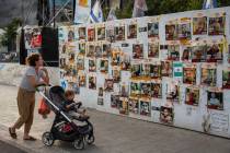 Passersby observe the photos of hostages held in the Gaza Strip that are plastered to the walls ...