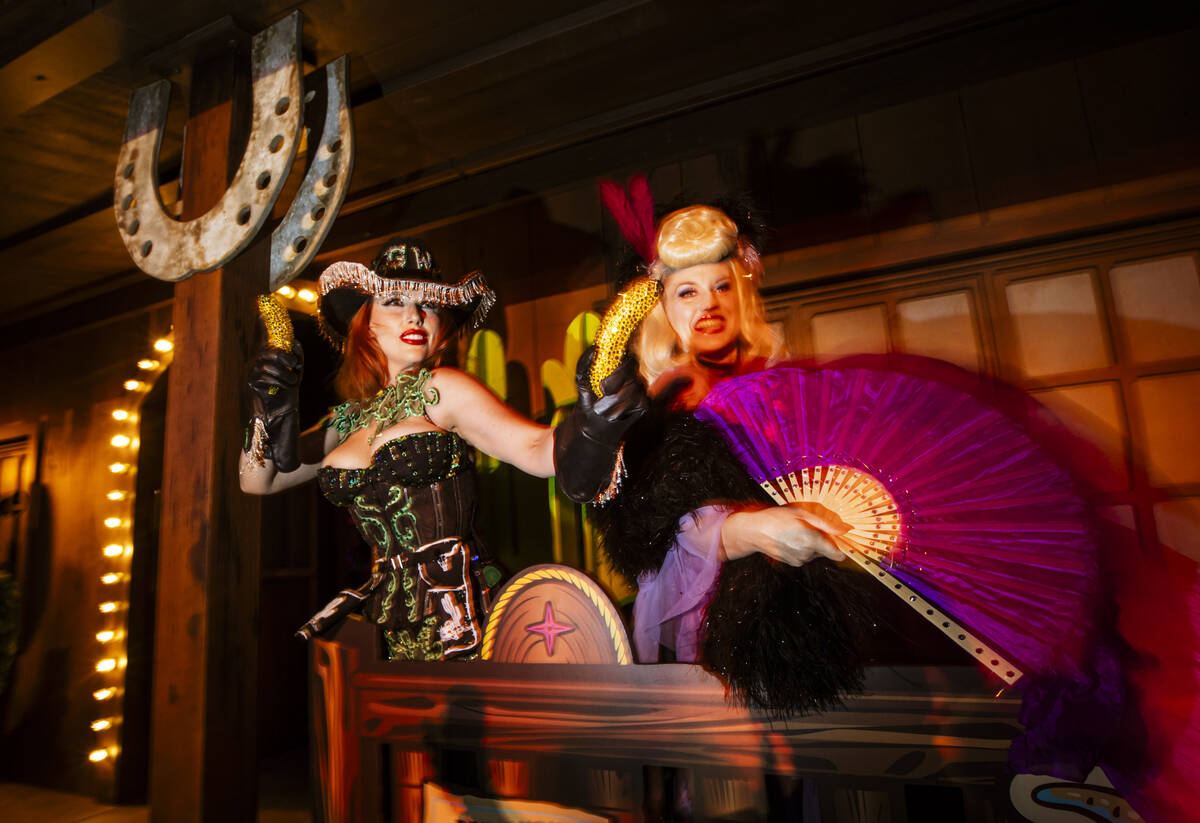 Burlesque performers Ginger Watson, left, and Vanessa Burgundy beckon attendees to come see a p ...
