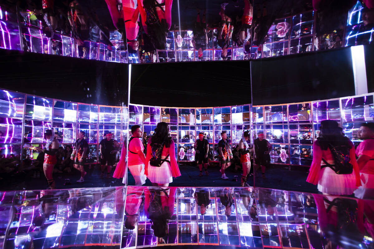 Attendees are reflected as they walk through an art installation during the first night of the ...