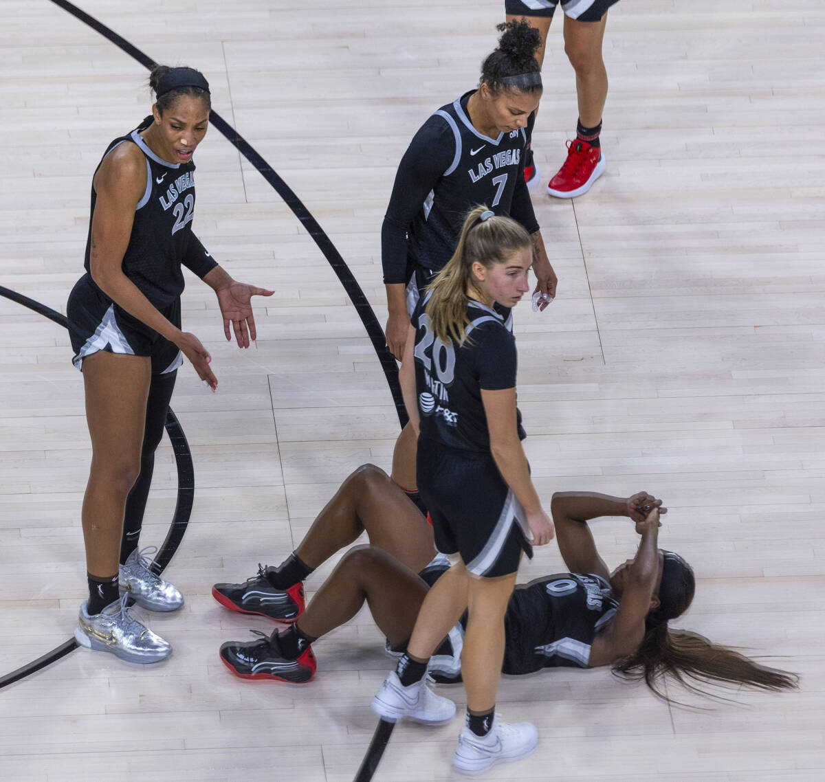 Aces guard Jackie Young (0) is down from a hard pick as center A'ja Wilson (22) questions an of ...