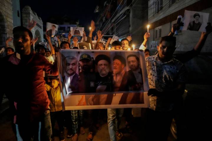 Shiite Muslims hold photos of Iranian President Ebrahim Raisi and others leaders shout slogans ...
