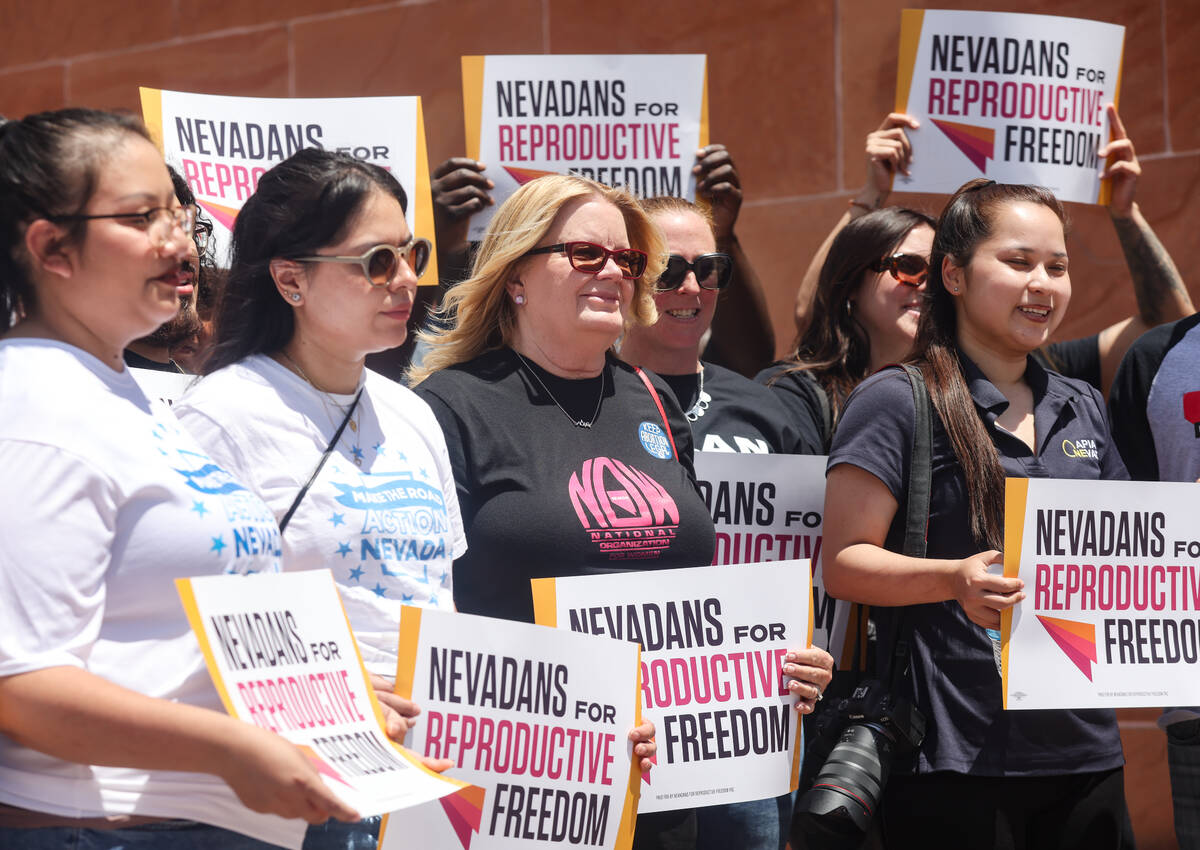 Supporters hold signs at a press conference regarding the over 200,000 signatures submitted to ...