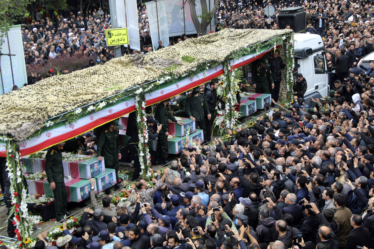 In this photo provided by Fars News Agency, mourners gather around a truck carrying coffins of ...