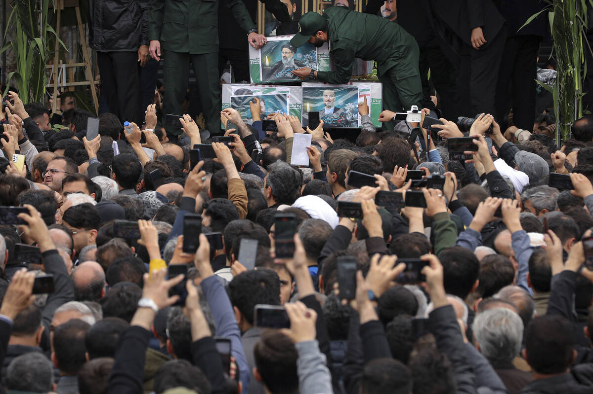 In this photo released by the Iranian Presidency Office, mourners gather around a truck carryin ...