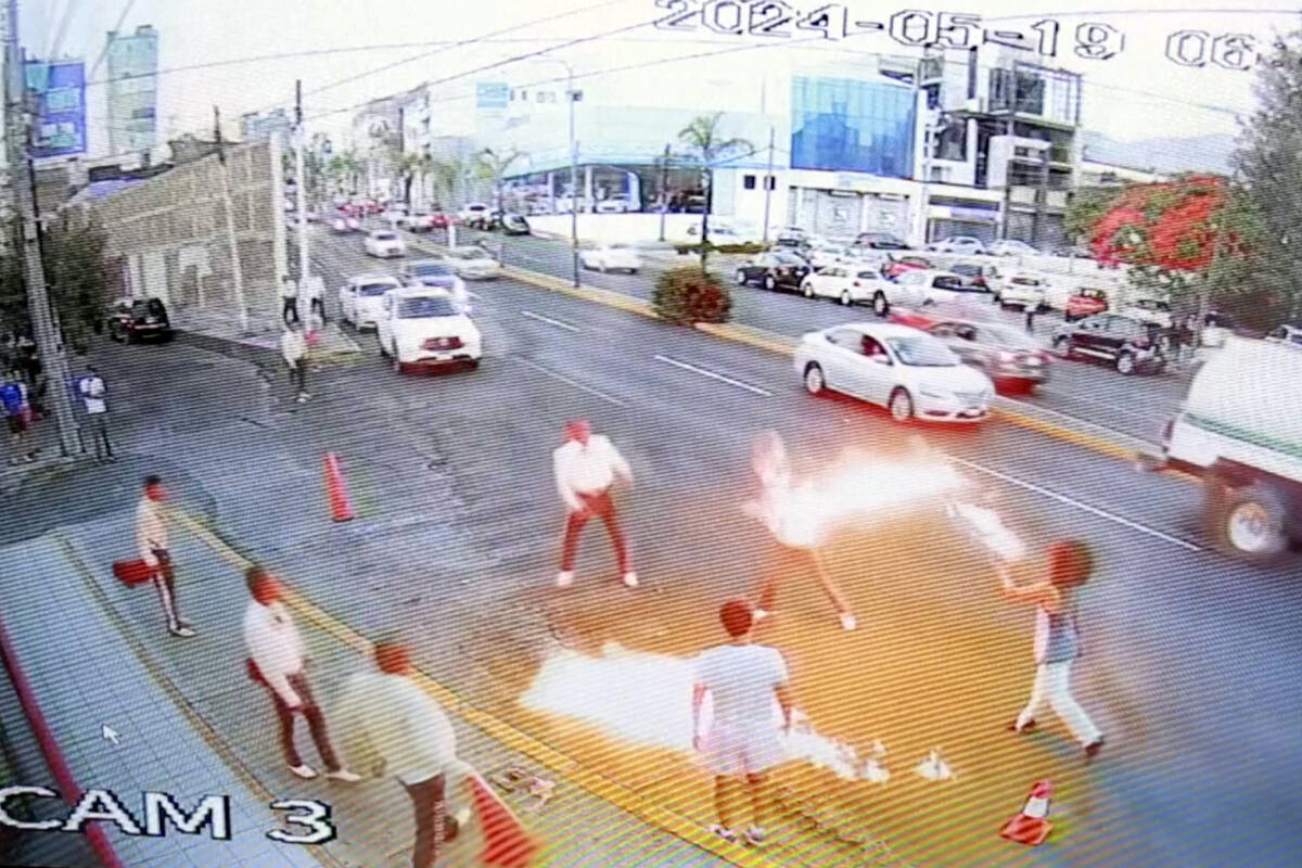 In this image taken from video provided by Jorge Toscano, a flame-swallower, right, and a group ...