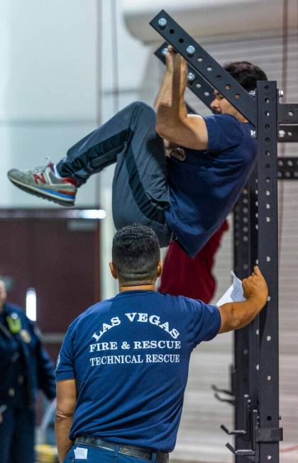 A participant hangs from a bar as he's observed during the Las Vegas Fire & Rescue free com ...