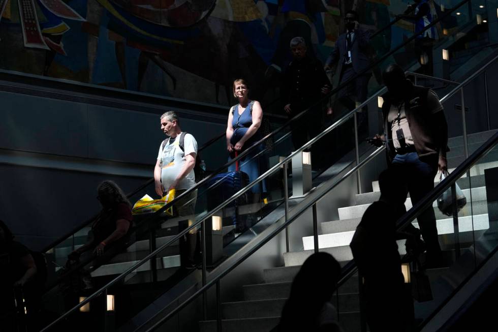 Travelers ride an escalator down to the concourse at Miami International Airport ahead of the M ...