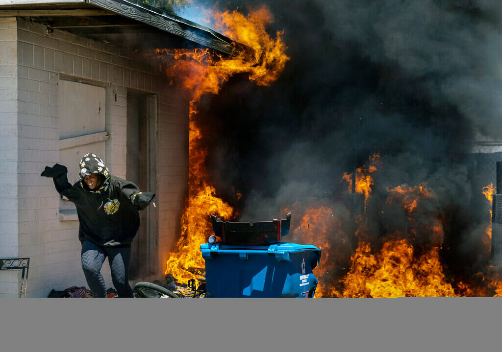 A woman runs out from a burning house after going back inside to check on others during a fire ...