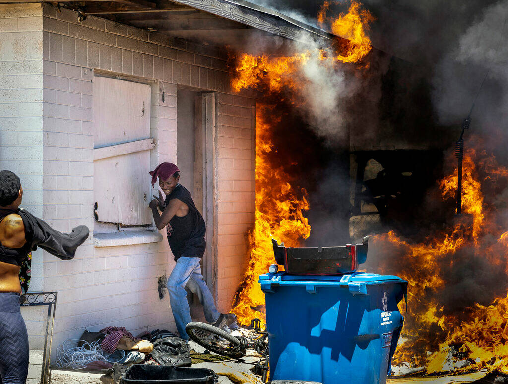 A man runs out from a burning house after going back inside to check on others during a fire be ...