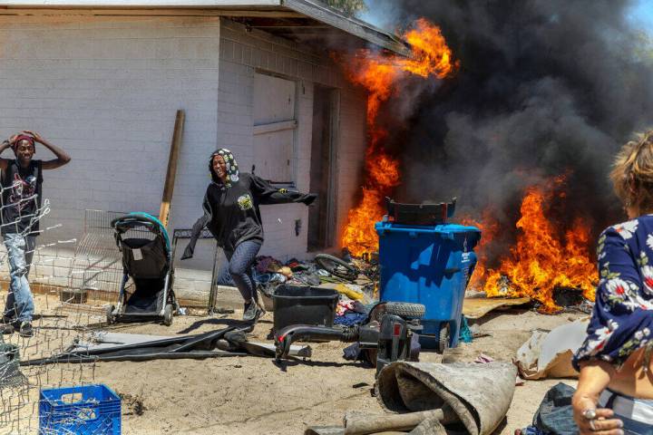 A woman runs out from a burning house after going back inside to check on others during a fire ...