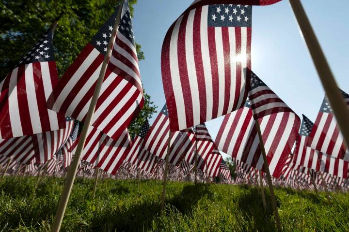 The sun shines through the flags in the Memorial Day Flag Garden on Boston Common, May 27, 2023 ...