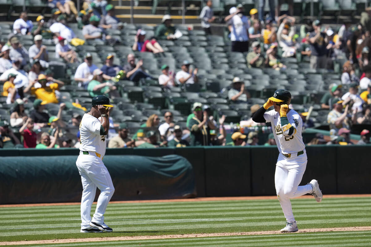 Oakland Athletics' Brent Rooker, right, celebrates with third base coach Eric Martins after hit ...