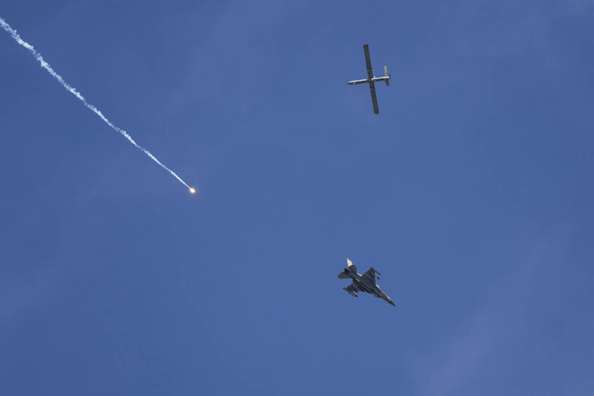 An Israeli fighter jet releases flares, and a drone is seen from Rafah, Gaza Strip, on Tuesday, ...