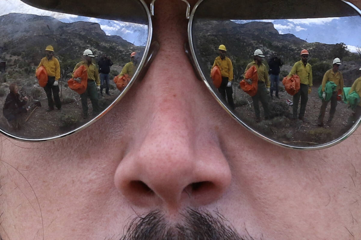 Firefighters from the Bureau of Land Management are reflected in the sunglasses of Andrew Merri ...