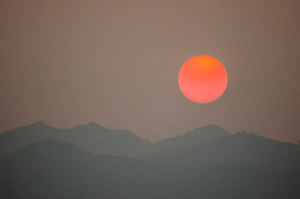 The sun, clouded by smoke from wildfires in California, sets behind the Spring Mountains Nation ...