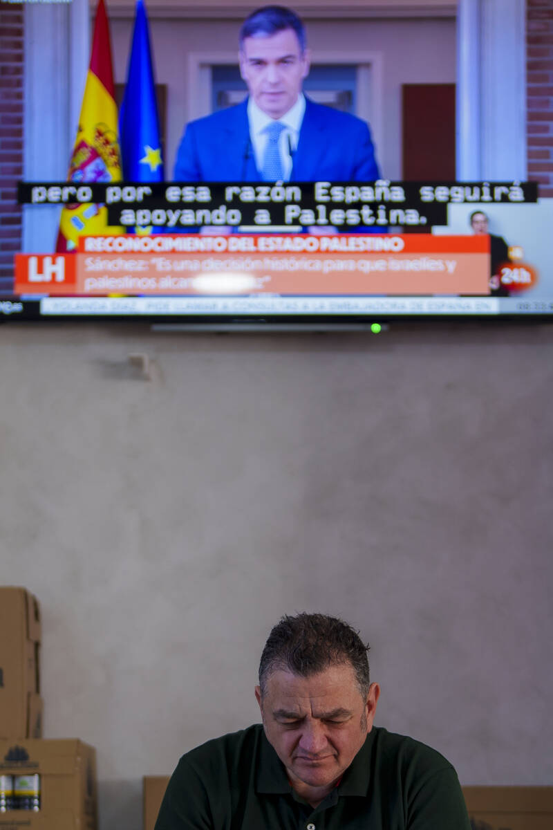 A customer sits in a restaurant while Spanish Prime Minister Pedro Sanchez appears on a televis ...