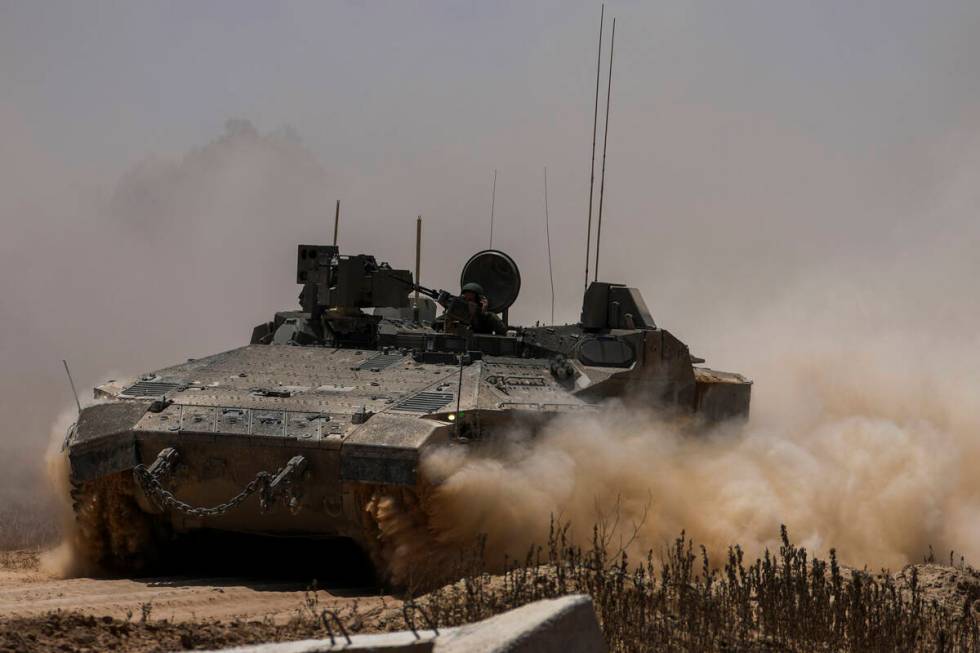 Israeli soldiers drive an APC near the Israeli-Gaza border, as seen from southern Israel, Wedne ...