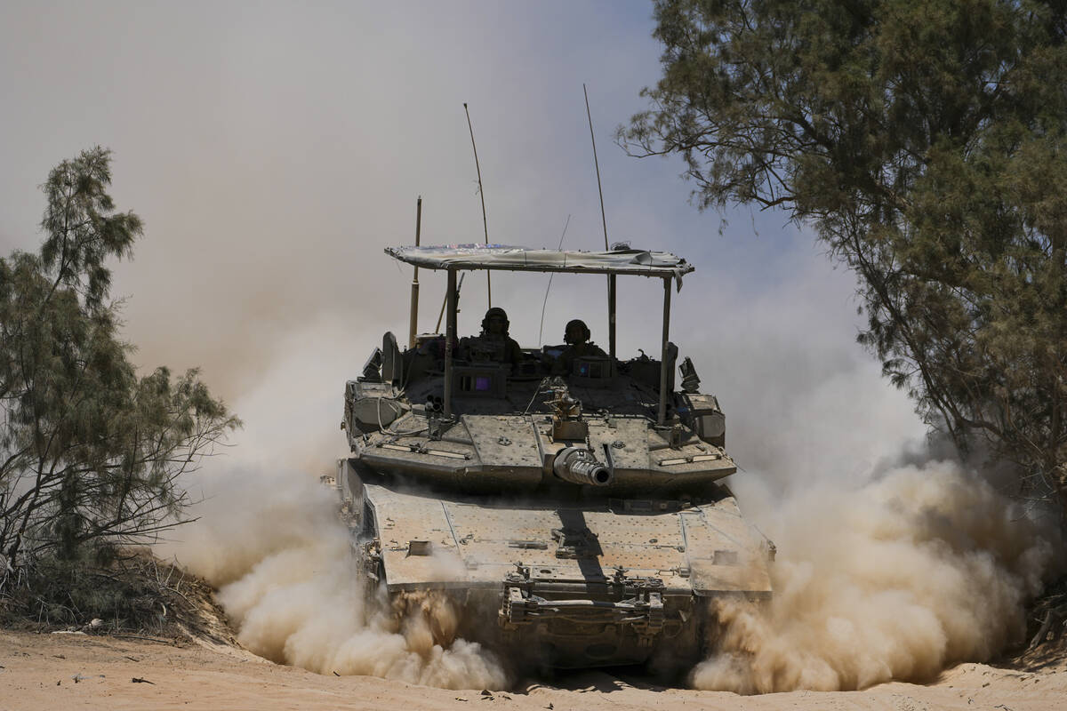 Israeli soldiers drive a tank near the Israeli-Gaza border, in southern Israel, Wednesday, May ...