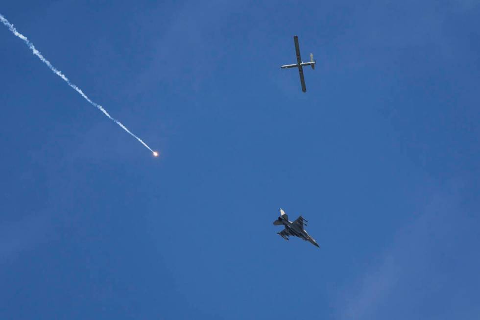 An Israeli fighter jet releases flares, and a drone is seen from Rafah, Gaza Strip, on Tuesday, ...